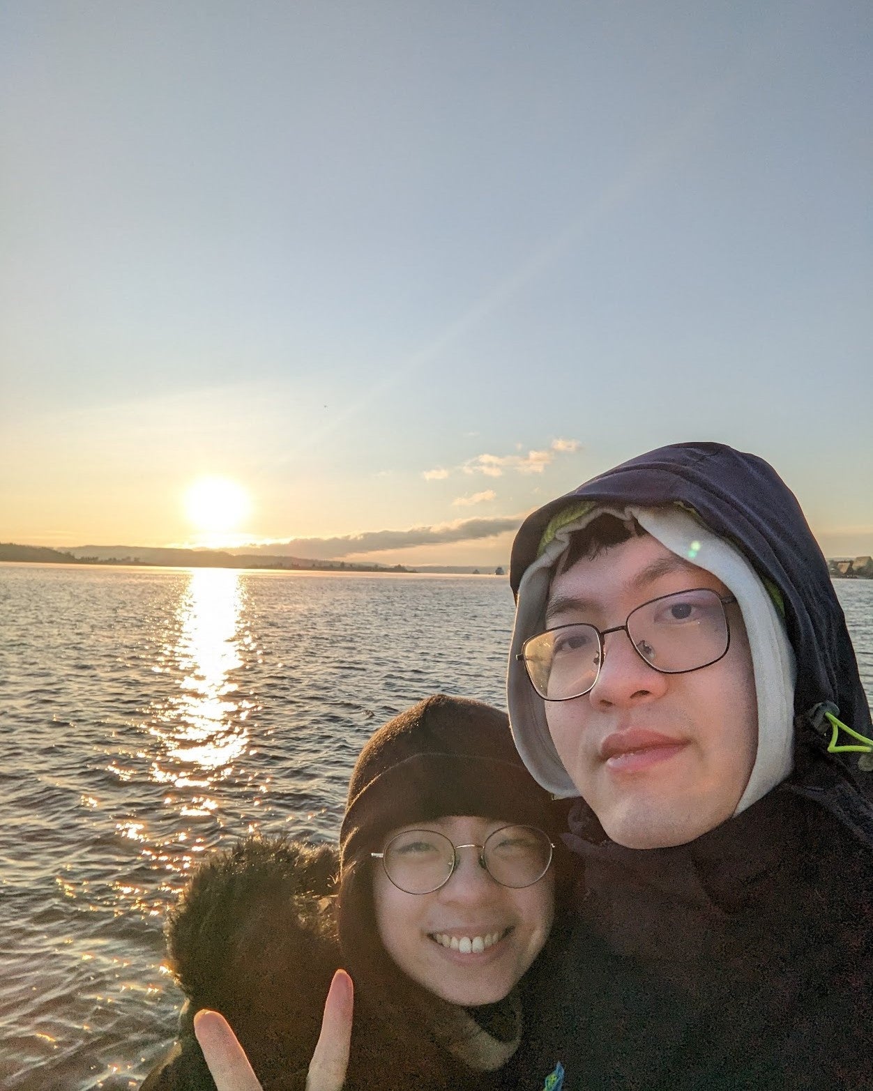 Stanley Miao and another person smiling in front of a sunrise.