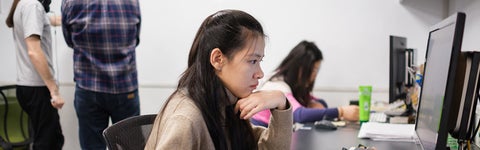 A student in a computer lab focused on her computer screen.