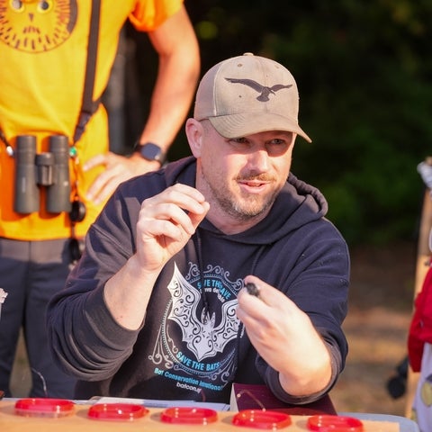 Liam McGuire holding a small bird and talking to students